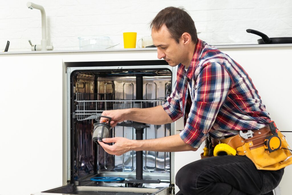 Worker repairing the dishwasher in the kitchen